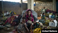 FILE - A 19-year-old woman and her children wait for their first hot meal in over two months at the Dosseye refugee camp in Chad. They arrived after fleeing violence in C.A.R.