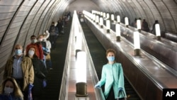 People wearing face masks and gloves to protect against coronavirus observe social distancing guidelines as they go down the subway on the escalator in Moscow, Russia, May 12, 2020.