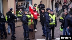 Protesters of the 'Gilets Jaunes' (Yellow Vests) movement await French President Emmanuel Macron's arrival, during his meeting with the mayors of the Saone-et-Loire department, in Autun, France Feb. 7, 2019. 