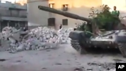 In this image made from amateur video released by the Ugarit News and accessed July 24, 2012, a Free Syrian Army solider drives a Syrian military tank in Aleppo, Syria.