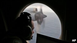 FILE - In this March 22, 2014, photo, a flight officer aboard a Royal Australian Air Force plane, searches for signs of missing Malaysia Airlines Flight MH370 in the southern Indian Ocean off Australia.