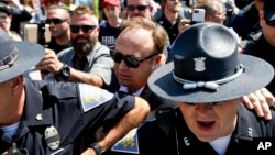 FILE - Alex Jones (C), an American conspiracy theorist and radio show host, is escorted out of a crowd of protesters after he said he was attacked in Public Square on July 19, 2016, in Cleveland, Ohio.