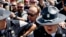 FILE - Alex Jones (C), an American conspiracy theorist and radio show host, is escorted out of a crowd of protesters after he said he was attacked in Public Square on July 19, 2016, in Cleveland, Ohio.