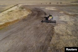 An agricultural worker operates farming equipment to plant wheat on farmland in Comodoro Py, outside of Buenos Aires, Argentina on June 21, 2022. (REUTERS/Matias Baglietto)