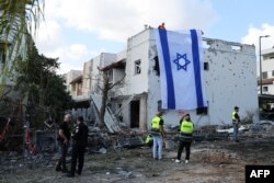 Bendera Israel dipasang di dinding bangunan rusak di Kiryat Bialik, Haifa, setelah serangan Hizbullah Lebanon pada 22 September 2024. (Foto: AFP)