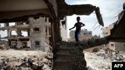 A Palestinian boy plays amid the rubble of his familiy's former house which was destroyed during the 50-day war between Israel and Hamas militants in the summer of 2014, in the Eastern Gaza City Shujaiya neighborhood, May 11, 2015,.