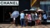 Mainland Chinese tourists wait outside a Chanel store at Hong Kong's Tsim Sha Tsui shopping district, Oct. 1, 2014, with part of it being blocked by protesters.
