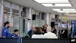 Passengers stand in line as they wait to pass through a Transportation Security Administration checkpoint at LaGuardia airport, Jan. 7, 2019, in New York.