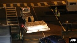 Police officers escort an airport vehicle transporting what is believed to be debris from a Boeing 777 plane that washed up on Reunion Island, at Roland Garros airport in Saint-Marie, Reunion Island, July 31, 2015.