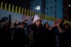 An anti-government protester, right, leads a chant as activists gather outside the state-run electricity company in Beirut, Lebanon, Dec. 21, 2019.