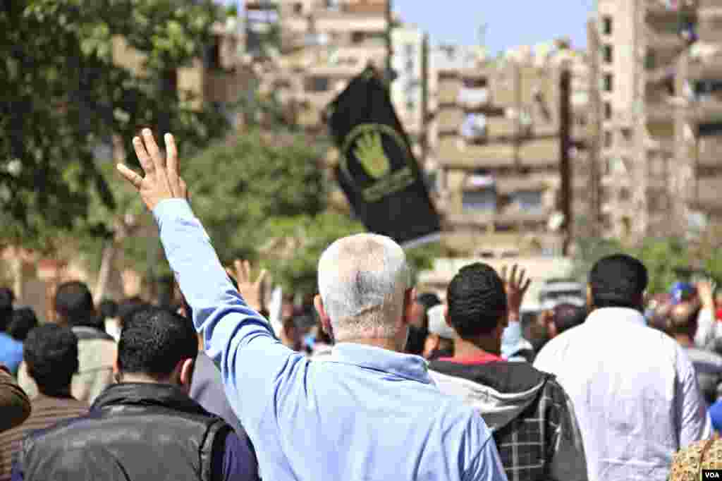 Protesters march through Cairo holding up four-fingers, a hand sign in memory of last year's deadly crackdown on supporters of ousted President Mohamed Morsi, March 28, 2014. (Hamada Elrassam/VOA)