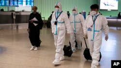 Miembros de la tripulación de vuelo de Air China, con trajes de protección caminan por el área de llegadas en el Aeropuerto Internacional de Los Ángeles en Los Ángeles, el martes 30 de noviembre de 2021.