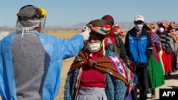 A health worker checks the temperature to residents from surrounding communities heading to the weekly food market in Coata, Peru, on July 8, 2020.