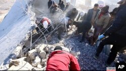 Image posted online Dec. 6, 2015, by supporters of Islamic State militant group on anonymous photo sharing website, shows Syrians inspecting damaged building in aftermath of airstrike that targeted areas in Raqqa, Syria. 