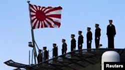 FILE - Sailors stand on the deck of the Izumo warship as it departs from the harbour of the Japan United Marine shipyard in Yokohama, south of Tokyo.