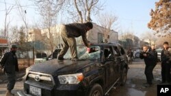 An Afghan driver removes a broken windshield of his car following the Friday's suicide attack and shooting in Kabul, Afghanistan, Saturday, Jan. 18, 2014.