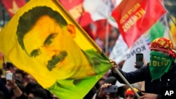 FILE - A youth holds a flag with the image of Abdullah Ocalan, the jailed leader of the rebel Kurdistan Workers' Party, or PKK, in Istanbul, Turkey, March 21, 2018. Ocalan called on his militant group on Feb. 27, 2025, to lay down its arms and dissolve.