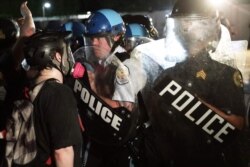 Un grupo de ciudadanos increpa a las fuerzas antidisturbios desplegadas en el céntrico parque de la Plaza Lafayette.