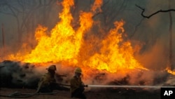FILE - Firefighters battle a wildfire along Highway 71 near Smithville, Texas. Wildfires that burn large areas of forests and send smoke into the air, contributing to pollution.