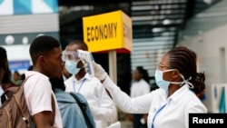 FILE - A health worker checks the temperature of a traveler as part of the coronavirus screening procedure at the Kotoka International Airport in Accra, Ghana, Jan. 30, 2020.