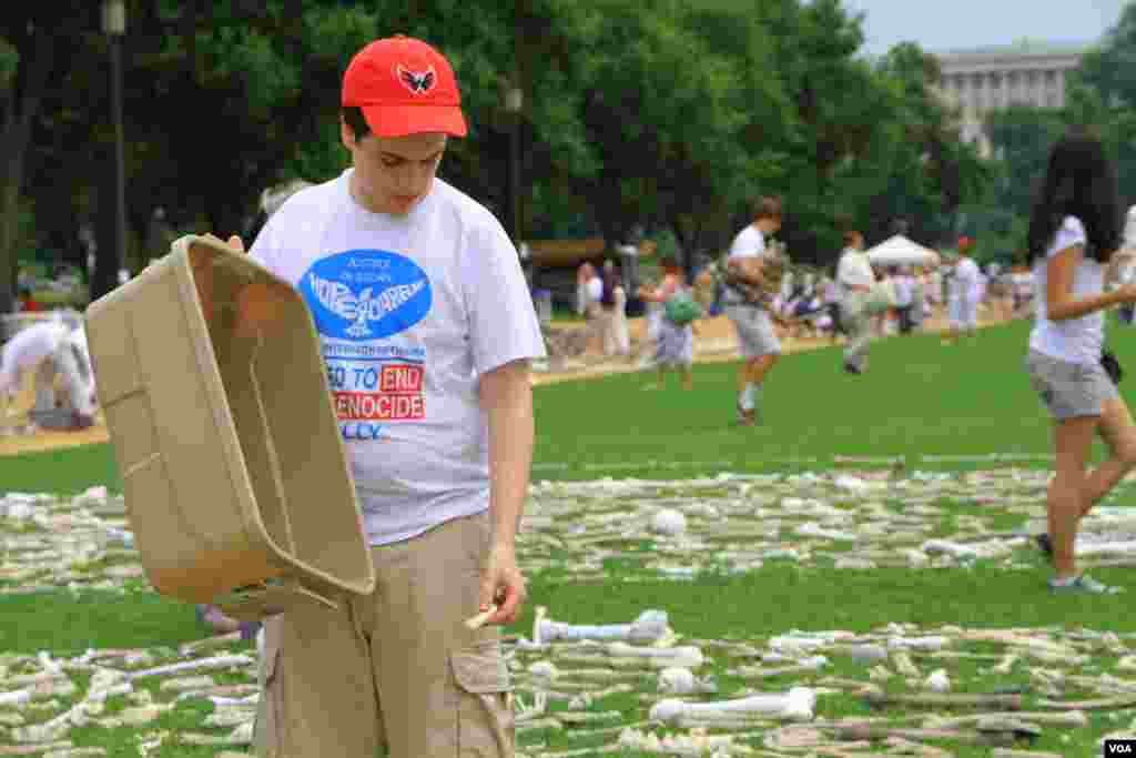 A volunteer lays artificial bones at the "One Million Bones" installation on the National Mall, Washington, D.C, June 8, 2013. (Jill Craig/VOA)