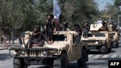 FILE - Armed Taliban fighters parade atop humvee vehicles as they celebrate the first anniversary of the withdrawal of US-led troops from Afghanistan, near the former US embassy in Kabul on Aug. 31, 2022. 