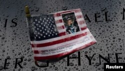 Rain drops rest near a U.S. flag with a picture of Walter Hynes at the south reflecting pool at the National 9/11 Memorial the day before the 19th anniversary of attacks in the Manhattan.