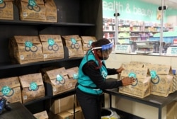 FILE - A worker sorts online orders before they are delivered to customers from a Checkers store, amid a nationwide coronavirus lockdown, in Johannesburg, South Africa, July 14, 2020.
