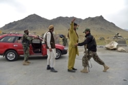 Afghan National Army soldiers search men at a road checkpoint on the outskirts of Kabul on April 29, 2021.