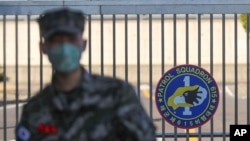 FILE - A South Korean marine wearing a mask stands in front of the navy base after a member of the unit was confirmed to have been infected with the coronavirus on Jeju Island, South Korea, Feb. 21, 2020.