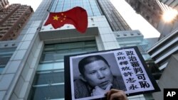 FILE - A placard with a photo of legal scholar Xu Zhiyong is raised by a demonstrator protesting against a Chinese court’s decision to sentence him in prison outside the Chinese liaison office in Hong Kong, Jan. 27, 2014.