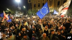 FILE - Protesters wave EU and Georgian national flags as they gather outside the parliament building in Tbilisi, Georgia, on April 15, 2024, to protest against a "foreign agent" law.