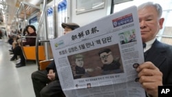 Seorang penumpang membaca koran dengan tajuk rencana KTT yang rencananya akan diadakan antara pemimpin Korea Utara Kim Jong-un dan Presiden AS Donald Trump (kanan) saat berada dalam kereta bawah tanah di Seoul, Korea Selatan, 10 Maret 2018. (Foto: dok).