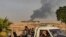 Syrians ride a pickup truck past smoke as Arab and Kurdish civilians flee following Turkish bombardment on Syria's northeastern town of Ras al-Ain in the Hasakeh province along the Turkish border on October 9, 2019.