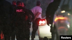 Police put the man suspected of killing at least three people during a shooting at a Planned Parenthood center in Colorado Springs, Colorado into a police vehicle, Nov. 27, 2015.