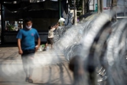 A migrant worker receives belongings over barbed wire in front of a closed shrimp market, amid the coronavirus disease outbreak, in Samut Sakhon province, in Thailand, Dec. 20, 2020.