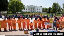 Para aktivis dengan mengenakan pakaian tahanan, menuntut penutupan pusat tahanan AS di Guantanamo, Kuba, dalam aksi protes di depan Gedung Putih (17/5).